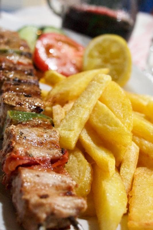 Souvlaki servito con pita grigliata, tzatziki e patatine: lo street food che racconta Atene meglio di qualsiasi monumento.