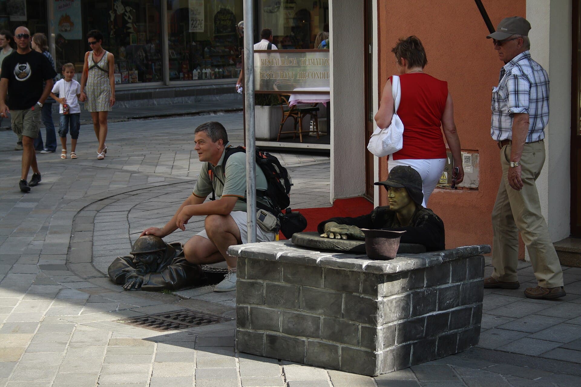 Čumil, l'operaio di bronzo che fa capolino da un tombino nel centro storico: la statua più amata e fotografata di Bratislava, qui imitata da un artista di strada.