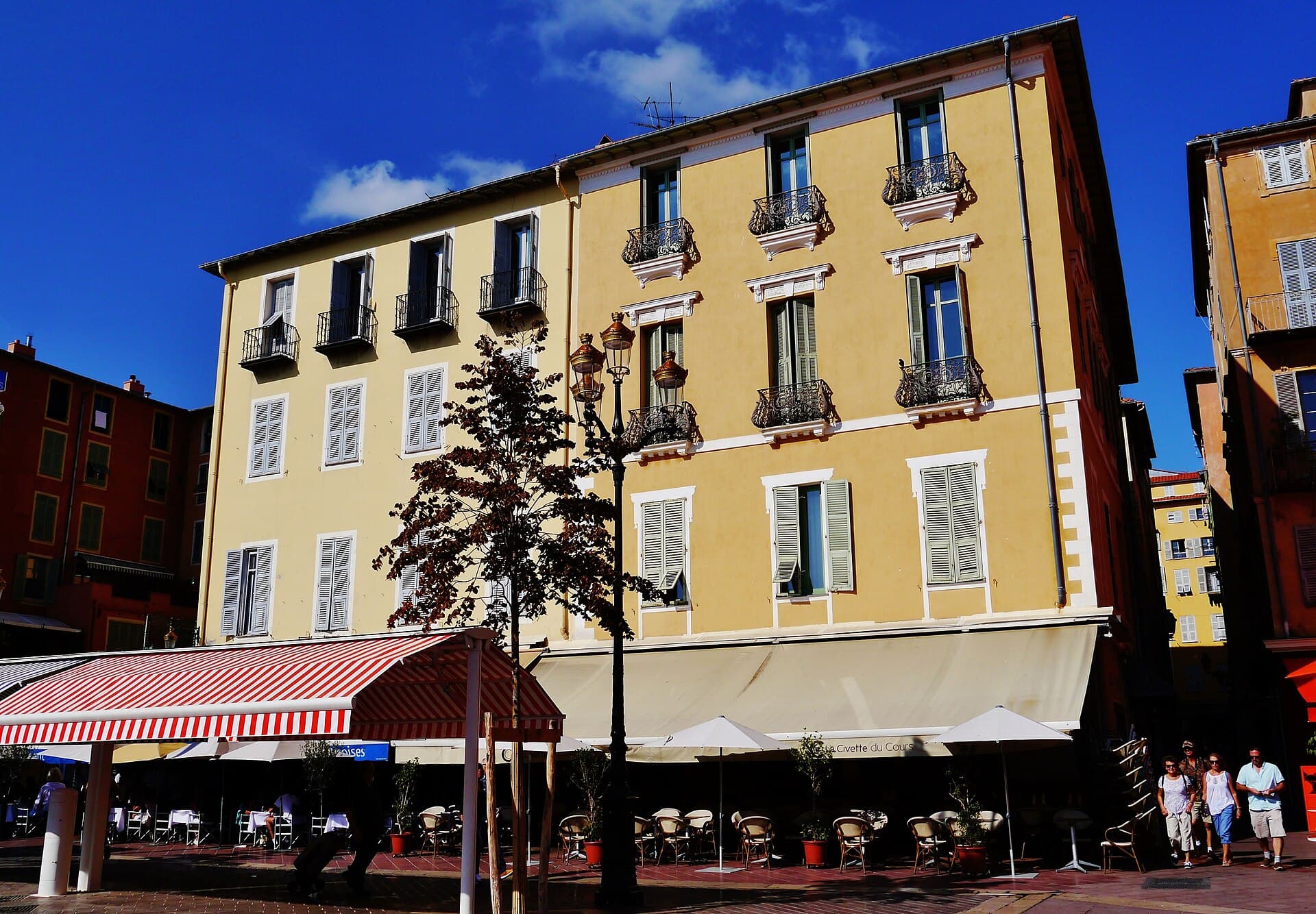 Il Cours Saleya nella città vecchia: di mattina mercato di fiori e prodotti locali, la sera tavoli e socca calda, sotto le facciate calde di Nizza.