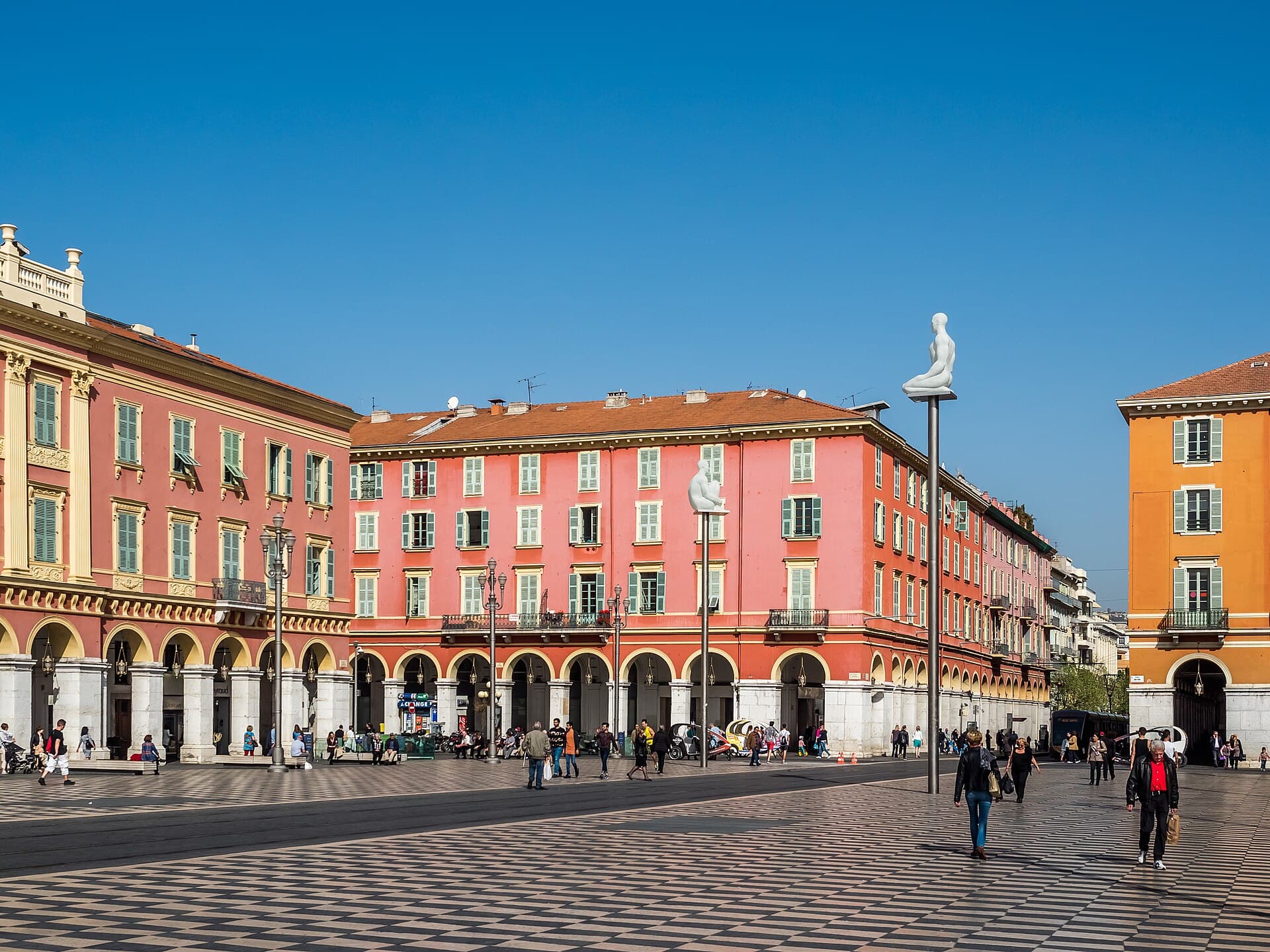 Place Masséna con il pavimento a scacchi e i palazzi rosso pompeiano: la piazza più scenografica di Nizza, dove la sera si accendono le sculture luminose sospese.